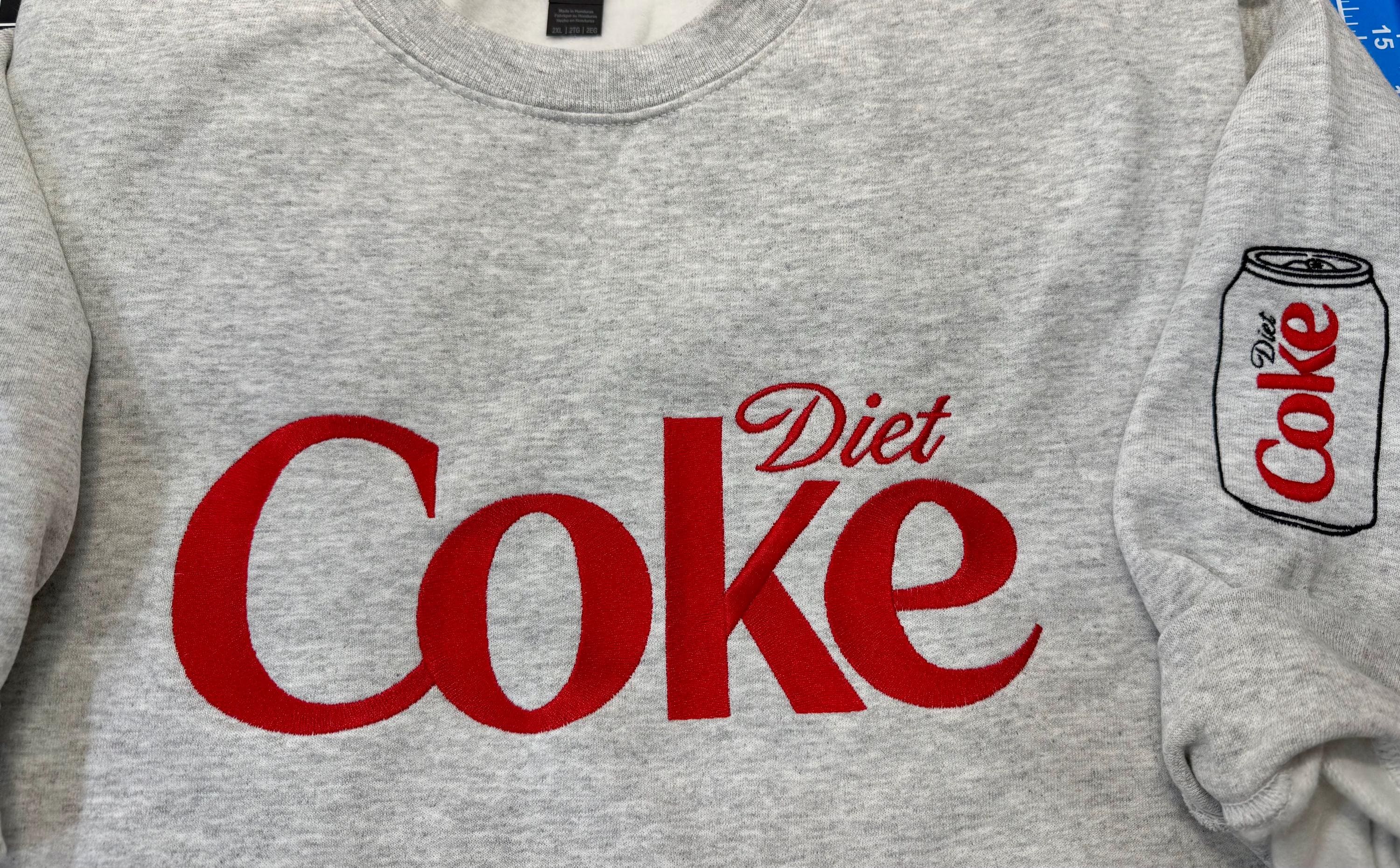 Diet Coke fans. Diet Coke embroidered cozy sweatshirt comes with a mini sized Diet Coke on the sleeve.
