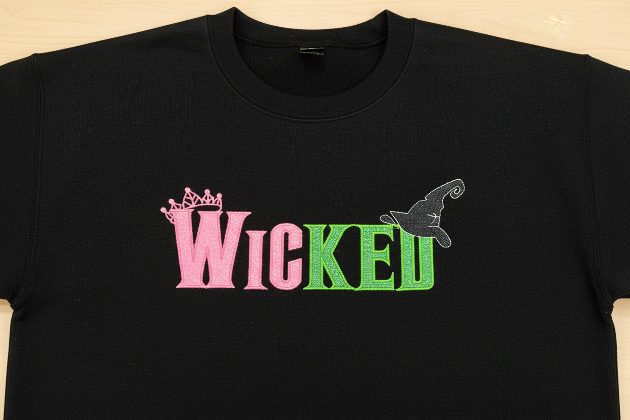 WICKED! This sparkly, embroidered wicked sweatshirt is perfect for Wicked fans. Includes a sleeve embellishment of a Green Broom/Pink Wand