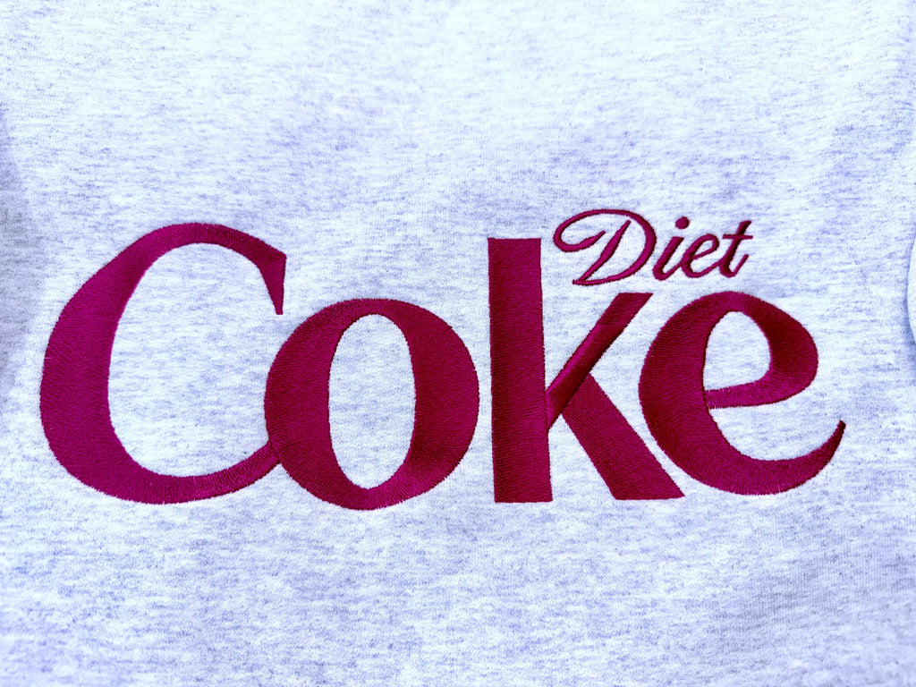 Diet Coke fans. Diet Coke embroidered cozy sweatshirt comes with a mini sized Diet Coke on the sleeve.