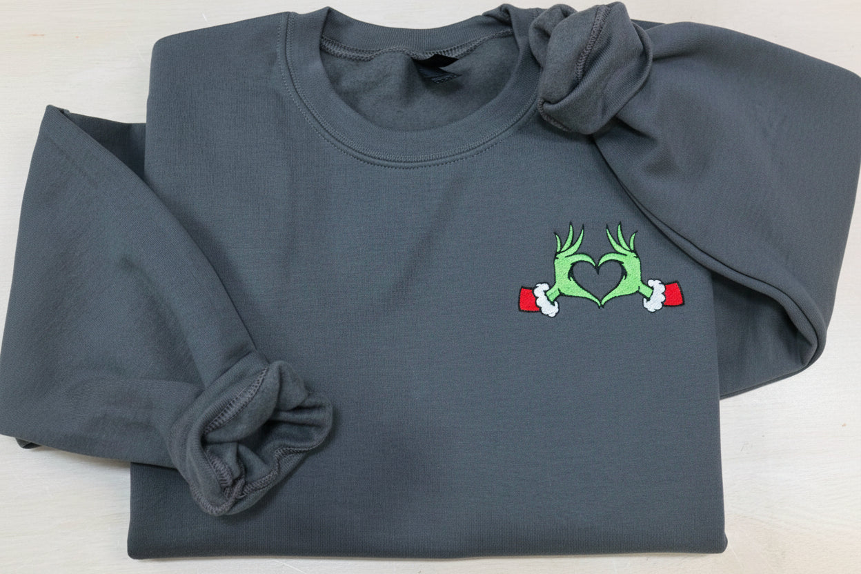 Show your Grinch Love with this Embroidered Sweatshirt. Featuring The Grinch hands shaped like a heart.
