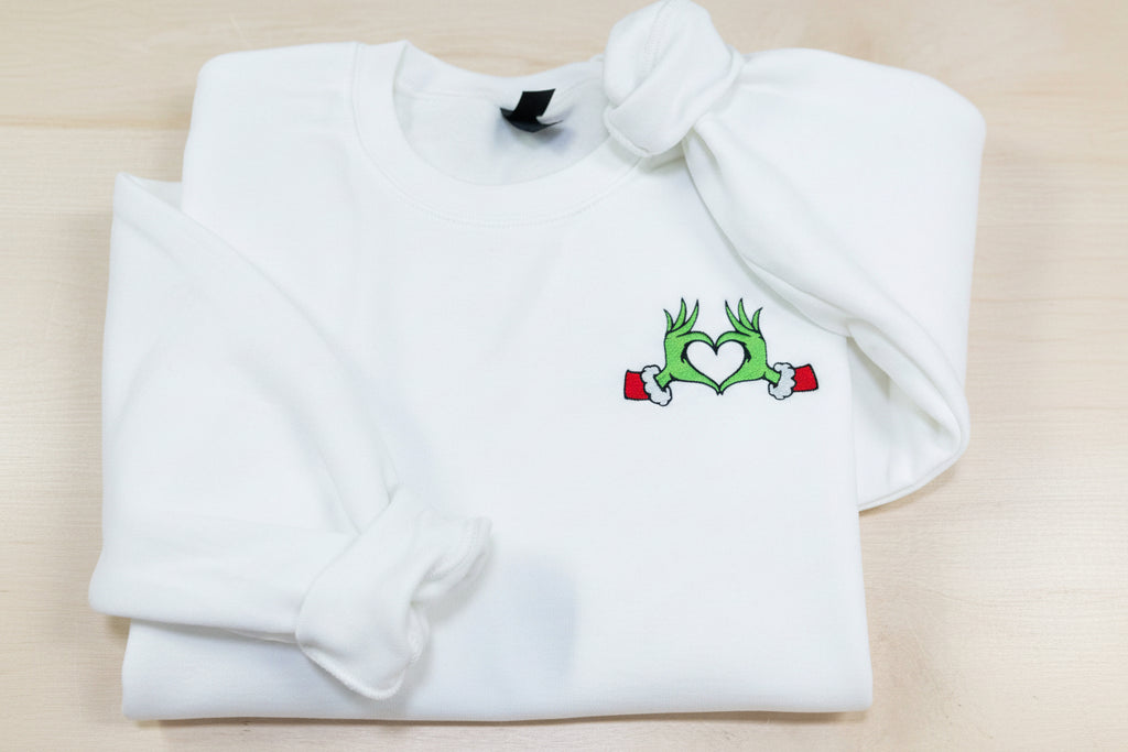 Show your Grinch Love with this Embroidered Sweatshirt. Featuring The Grinch hands shaped like a heart.