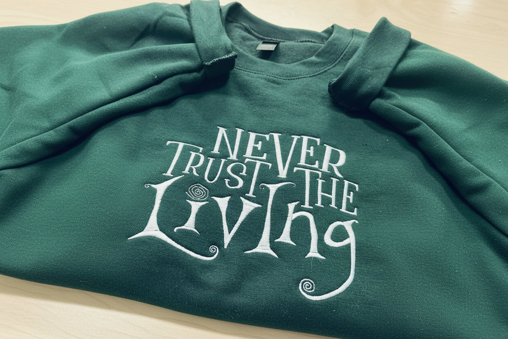 Coraline “Never Trust The Living” Season Embroidered Sweatshirt. Keeps you warm and cozy for those chilly nights.