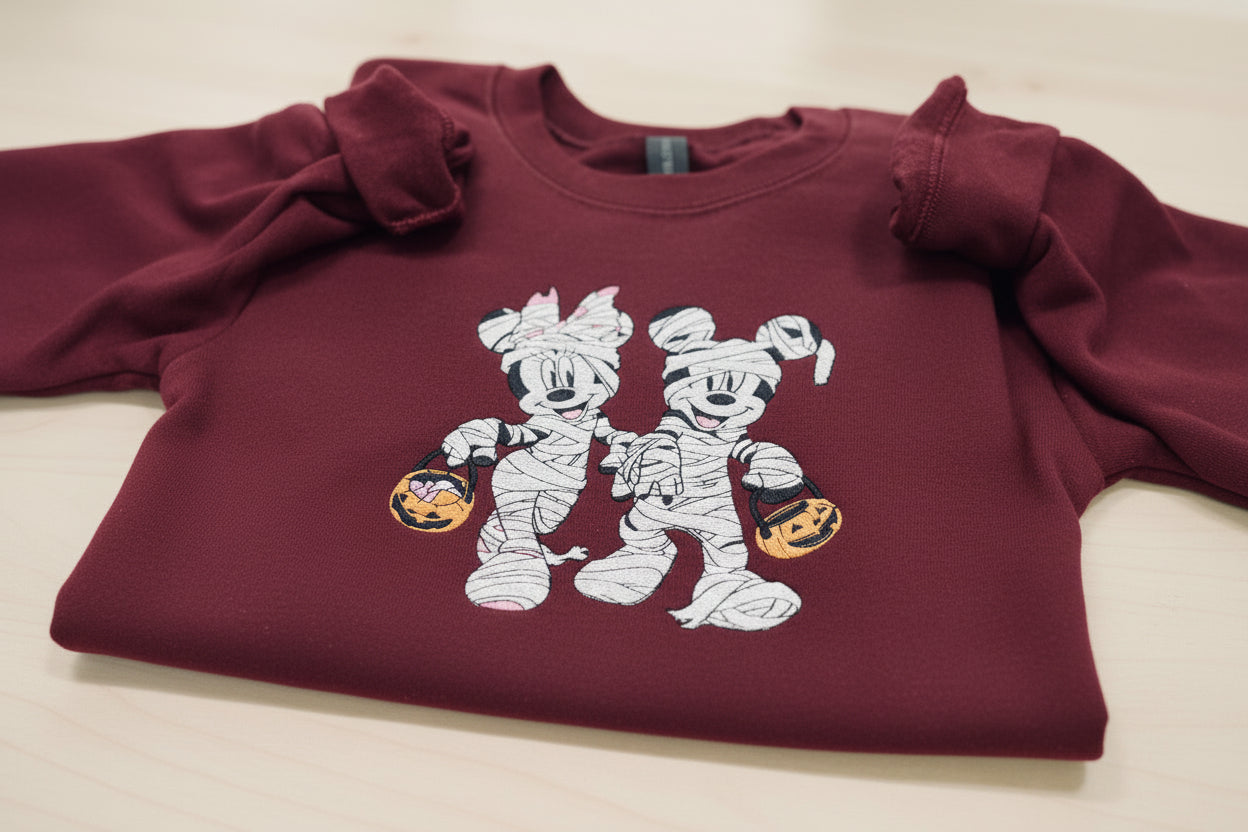 Halloween fun with our cozy embroidered sweatshirt featuring “Mickey & Minnie” all dressed up in their mummy costumes. Trick or Treat!