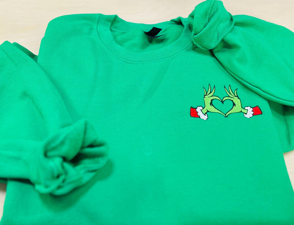 Show your Grinch Love with this Embroidered Sweatshirt. Featuring The Grinch hands shaped like a heart.
