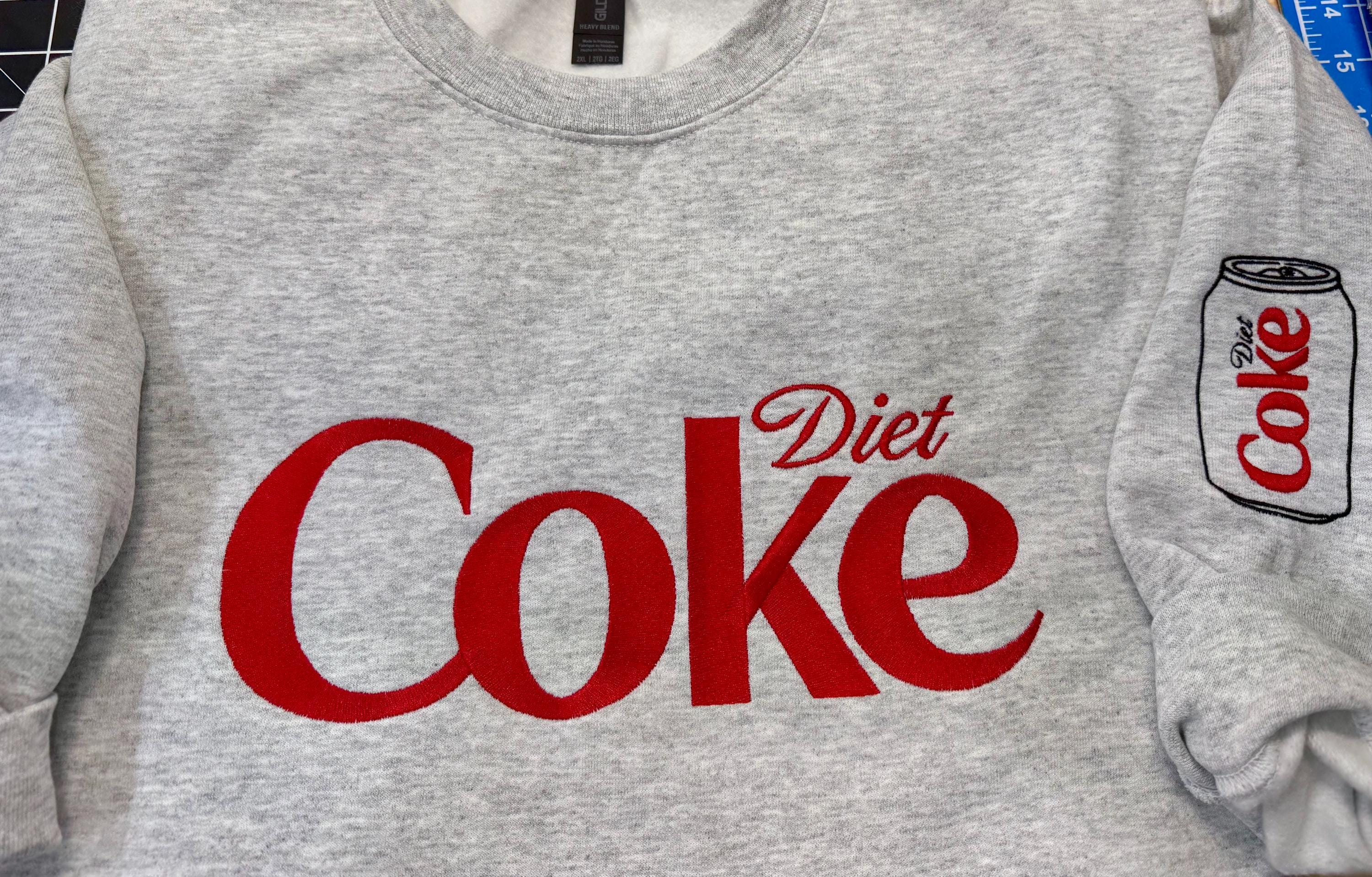 Diet Coke fans. Diet Coke embroidered cozy sweatshirt comes with a mini sized Diet Coke on the sleeve.