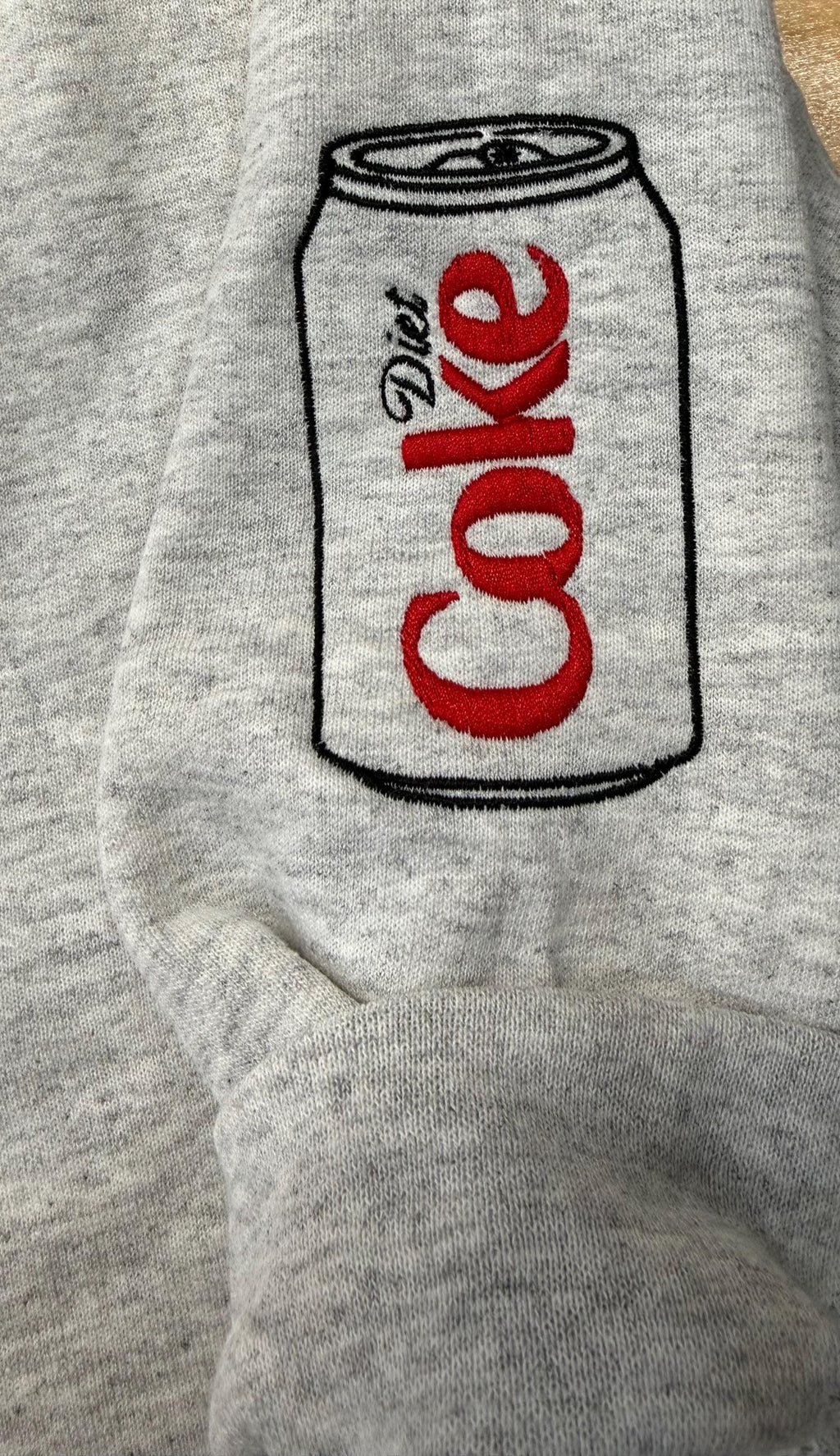 Diet Coke fans. Diet Coke embroidered cozy sweatshirt comes with a mini sized Diet Coke on the sleeve.
