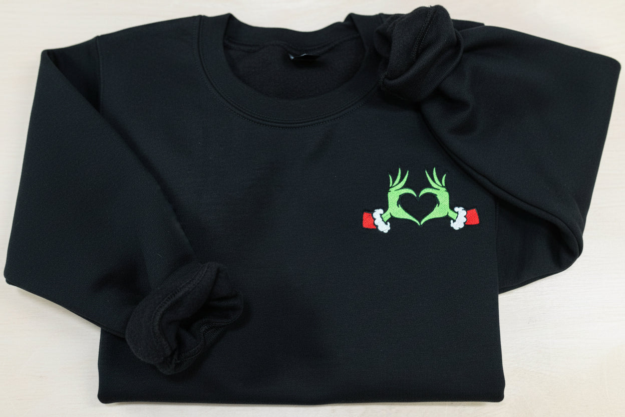Show your Grinch Love with this Embroidered Sweatshirt. Featuring The Grinch hands shaped like a heart.