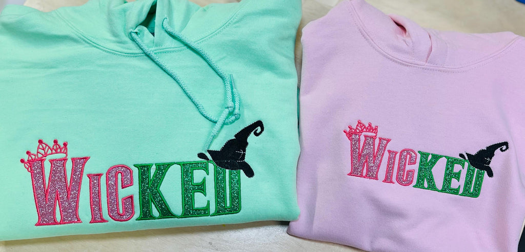 WICKED! This sparkly, embroidered wicked sweatshirt is perfect for Wicked fans. Includes a sleeve embellishment of a Green Broom/Pink Wand
