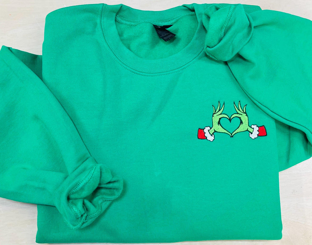 Show your Grinch Love with this Embroidered Sweatshirt. Featuring The Grinch hands shaped like a heart.