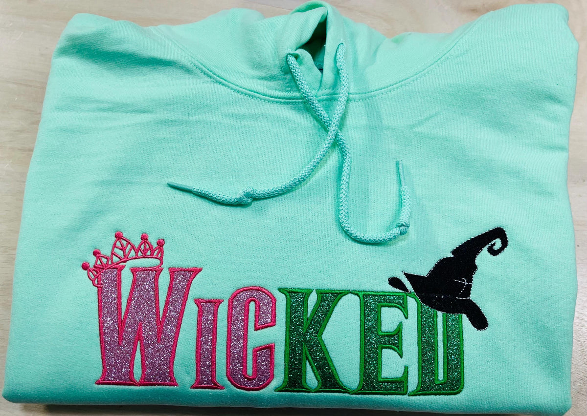WICKED! This sparkly, embroidered wicked sweatshirt is perfect for Wicked fans. Includes a sleeve embellishment of a Green Broom/Pink Wand