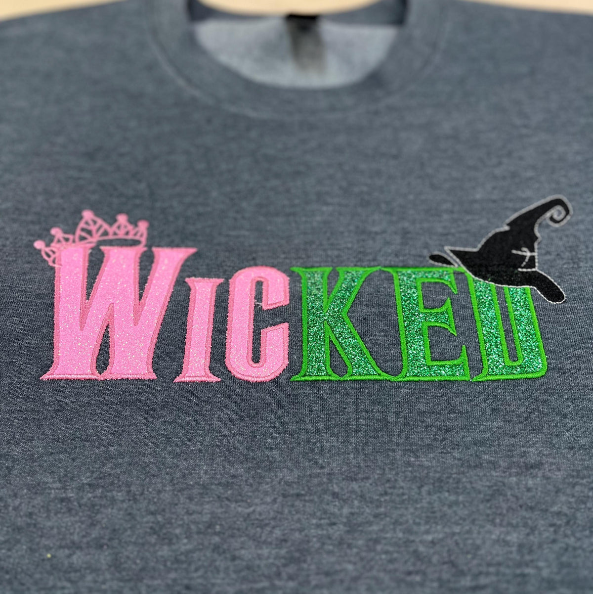 Youth WICKED! This sparkly, Wicked embroidered sweatshirt is perfect for Youth. Complete with sleeve embellishment Broom and Wand Vinyl